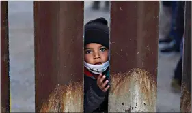  ?? (AP Photo/ Ross D. Franklin) ?? A young boy, part of several asylum-seeking families participat­ing in a Las Posadas event at the U.S.-Mexico border wall, peers into the U.S. from Agua Prieta, Mexico, on Dec. 15 as seen from Douglas, Ariz. People on each side of the border celebrated Las Posadas as they have done for decades, a centuries-old tradition practiced in Mexico that re-enacts Mary and Joseph’s search for refuge in Bethlehem.