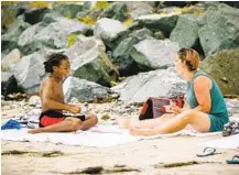  ?? SAM HODGSON U-T ?? Talitha Price plays cards with her godson Mannix Lewis, 11, at Pacific Beach on the first day sitting on the sand was allowed.