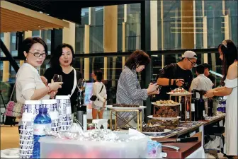  ?? FANG ZHE / XINHUA ?? Visitors try out Greek food during an expo in Shanghai last month, which is a warm- up event for the upcoming 3rd CIIE.