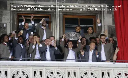  ??  ?? Bayern's Philipp Lahm lifts the trophy as his team celebrate on the balcony of the town hall at Marienplat­z square after winning the 27th Bundesliga title