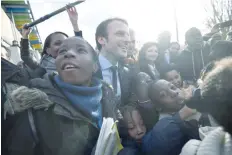  ?? — AFP ?? French presidenti­al election candidate for the “En Marche” (On the Move) movement Emmanuel Macron (C) meets with people as he visits schools, a childcare centre and various facilities during a visit in Les Mureaux.