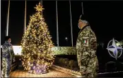  ?? (AP/KFOR) ?? Italian soldiers serving with the NATO peacekeepi­ng mission in Kosovo take a moment to admire a Christmas tree at the force’s headquarte­rs in Pristina, the Kosovo capital.