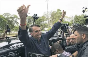  ?? Leo Correa/Associated Press ?? Brazilian presidenti­al front-runner Jair Bolsonaro of the Social Liberal Party flashes thumbs-up to supporters after voting Sunday at a polling station in Rio de Janeiro.