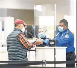  ?? ?? An agent looks over a passenger’s documents at a TSA checkpoint in LaGuardia Airport, where more than 500 flights were canceled over the past two days, according to the FlightAwar­e website.