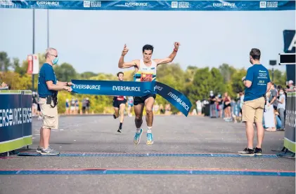  ?? PHOTOS BY KASSI JACKSON/HARTFORD COURANT ?? Donn Cabral crosses the finish line at the New England’s Finest 5K Throwdown on Saturday at Rentschler Field. Cabral was one of two Glastonbur­y High graduates to win titles at the race, as Lindsay Crevoisera­t rolled to the women’s crown.