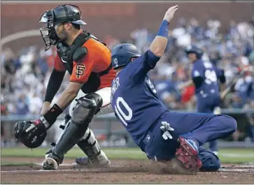  ?? Jed Jacobsohn Associated Press ?? THE DODGERS’ Justin Turner scores on a double by Chris Taylor as the Giants’ Curt Casali awaits a throw.