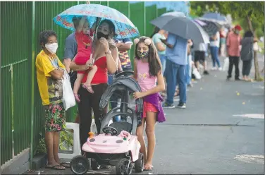  ?? (AP/Andre Penner) ?? People wait in line outside a public school to get a shot of China’s Sinovac CoronaVac vaccine in Serrana, Brazil. Brazil’s Butantan Institute has started a mass vaccinatio­n of the city’s entire adult population, about 30,000 people, to test the virus’ behavior in response to the vaccine.