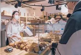  ?? ANDREA MANTOVANI/THE NEW YORK TIMES ?? Charlotte Noel sells baguettes Dec. 19 at a bakery in Paris. The price of a traditiona­l baguette is projected to rise up to 10 cents in 2022.