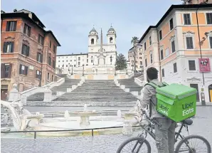  ??  ?? KEEPING FAITH: An Uber Eats delivery man stands by the Spanish Steps at the deserted Piazza di Spagna in central Rome on Friday.
