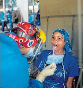  ?? /AFP ?? A health worker performs a swab test for Covid-19 on another health worker at the screening tents set up at the Charlotte Maxeke Hospital in Johannesbu­rg.
Testing time: