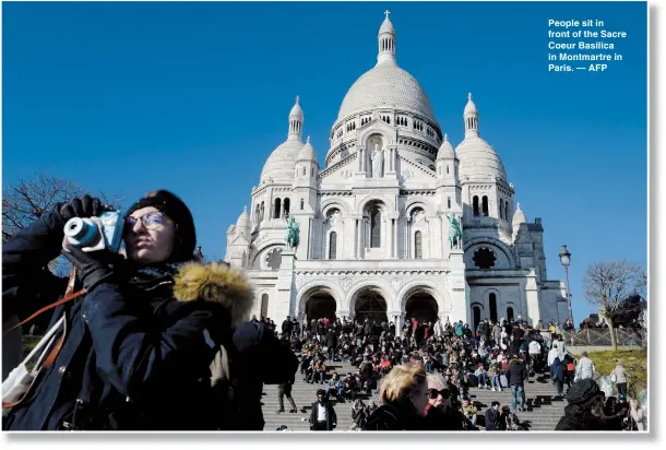  ??  ?? People sit in front of the Sacre Coeur Basilica in Montmartre in Paris. — AFP