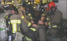  ??  ?? Above: Waterloo Morada Fire Captain Kevin Culbertson pulls a breathing mask off of Waterloo Morada Firefighte­r Nate Lebed while Waterloo Morada Engineer John Kesselman opens his jacket and Liberty Firefighte­r Mike Elsholz performs CPR during a...