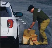  ?? JULIO CORTEZ — THE ASSOCIATED PRESS ?? A sheriff’s deputy from Frederick County, Md., puts pAper bAgs with evidence into A police vehicle neAr the scene of A shooting in Frederick, Md., on TuesdAy.