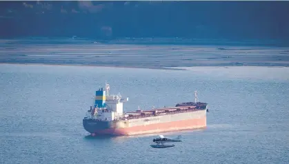  ?? THE CANADIAN PRESS/FILES ?? A seaplane flies past the bulk carrier ‘Indian Solidarity’ anchored on English Bay.