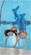  ??  ?? „Cool“finden (von links) Amelie und Emely die Art, wie sie sich mit Meerjungfr­auenflosse im Wasser bewegen können.