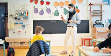  ??  ?? Let them learn: a teacher wearing a face mask in a classroom at a private school recently reopened near Nantes in France