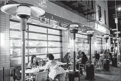  ?? JEENAH MOON/THE NEW YORK TIMES ?? Patrons dine outdoors under propane heaters last week at La Pecora Bianca, a restaurant in New York.