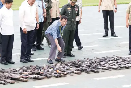  ?? AP FOTO ?? MARKED FOR DESTRUCTIO­N. President Rodrigo Duterte inspects guns and weapons captured, confiscate­d, surrendere­d and recovered from the enemy during the siege in Marawi, before they are destroyed. Congress voted overwhelmi­ngly Wednesday to approve...