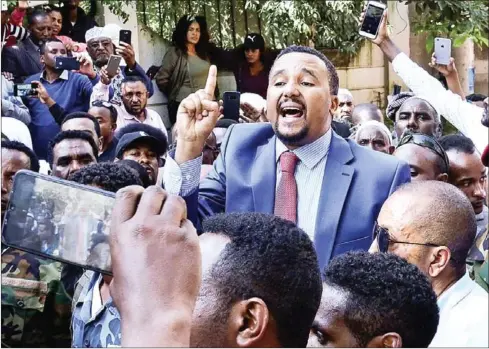  ?? AFP ?? Jawar Mohammed (centre), a member of the Oromo ethnic group who has been a public critic of Abiy despite initally supporting him, addresses supporters outside his home in Addis Ababa after he accused the Nobel Peace Prize laureate of ‘acting like a dictator’.