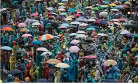  ?? Photograph: Jack Taylor/AFP/Getty Images ?? Pro-democracy protesters shelter from the rain under ponchos and umbrellas at Victory Monument in Bangkok on Sunday.