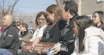  ?? ?? Rocio Lasso, mother of Chicago Police Officer Andres Mauricio Vasquez Lasso, sits with her family Saturday as they hold a street sign in honor of her son at the corner of Marquette Road and Lawndale Avenue in West Lawn.