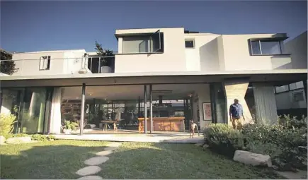  ?? Photograph­s by Genaro Molina Los Angeles Times ?? PAUL HIBLER and dog Maya stand in front of the Venice home. The bottom f loor is designed to be open to the walk street it faces.