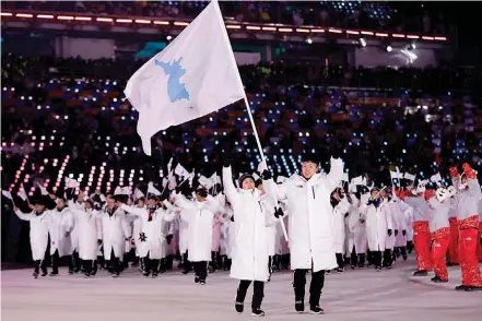  ?? AP ?? North Korea’s Hwang Chung Gum and South Korea’s Won Yun- jong lead the joint Korean contingent while carrying a unified Korea flag at the opening ceremony of the 2018 Winter Olympics in Pyeongchan­g, South Korea, on Friday. —