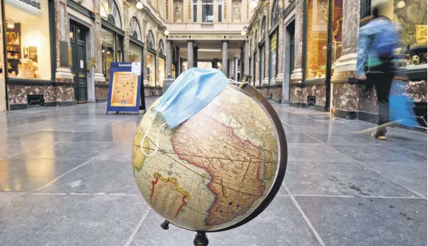  ??  ?? A globe with a surgical mask is seen on the floor of the Galeries Royales Saint-Hubert, Brussels, Belgium, Oct. 28, 2020.