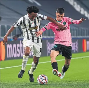  ?? MARCO BERTORELLO AFP VIA GETTY IMAGES ?? Juventus’ midfielder Juan Cuadrado, left, fights for the ball with Barcelona’s Pedri in UEFA Champions League action in Turin. Barcelona and Lionel Messi beat Juventus 2-0.