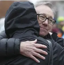  ??  ?? SOLEMN SUPPORT: Richard Curran, right, of Cambridge, hugs his friend Ed Marakovitz, left, of Somerville, after addressing attendees at a rally on distracted driving.