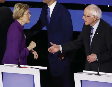  ?? AP ?? SOCIALIST HAND OUT: Democratic presidenti­al candidates Sen. Elizabeth Warren and Sen. Bernie Sanders interact after the debate on Tuesday.