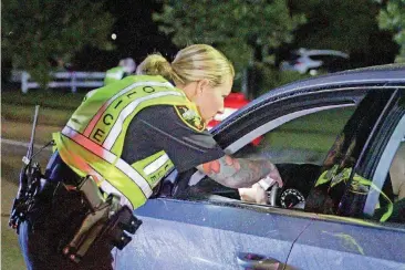  ??  ?? Officer Teresa Orr with the Jacksonvil­le Police Department speaks with a driver at a checkpoint in Jacksonvil­le, N.C.
[AP FILE PHOTO]