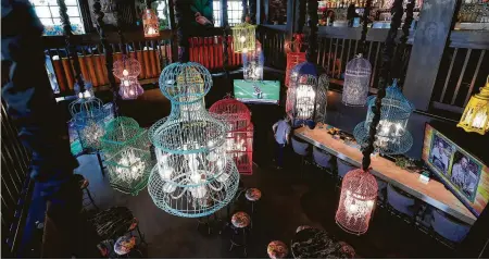  ?? Karen Warren photos / Staff photograph­er ?? Present Company’s décor features colorful birdcage chandliers.