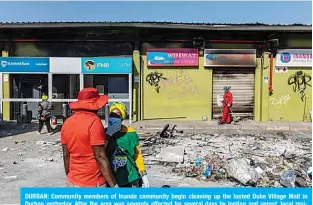  ?? —AFP ?? DURBAN: Community members of Inanda community begin cleaning up the looted Dube Village Mall in Durban yesterday. After the area was severely affected for several days by looting and unrest, local residents are trying to return to normality.