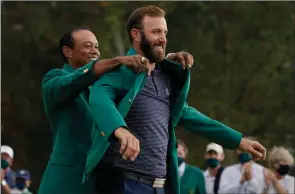  ?? The Associated Press ?? Tiger Woods helps Dustin Johnson with his green jacket after his victory at the Masters golf tournament on Nov. 15 in Augusta, Ga.