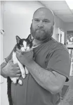  ?? PHOTOS BY JODI CAMP/THE MESSENGER VIA AP ?? Richard Bales, an animal control officer for the Hopkins County Animal Shelter, holds 14-year-old Frida, a cat rescued in Dawson Springs after the mid-december tornado. Frida came to the shelter dehydrated and malnourish­ed.