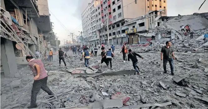  ?? MOHAMMED ABED / AFP ?? Guerra. Bombeiros e moradores palestinos procuram por vítimas em meio aos escombros de torre de 13 andares que desabou após ser atingida por ataque aéreo de Israel em Gaza