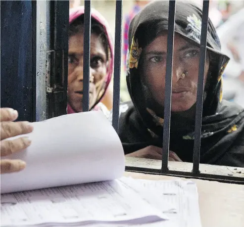  ?? ANUPAM NATH / THE ASSOCIATED PRESS ?? Women check if their names are included in Assam’s National Register of Citizens in Mayoung, India, on Monday. Residents unable to prove they or their families lived in the state before March 24, 1971 have been declared foreigners.