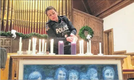  ?? ALISON JENKINS/JOURNAL PIONEER ?? Const. Ashley Davis lights a candle for one of the École Polytechni­que victims at Trinity United Church on Thursday.
