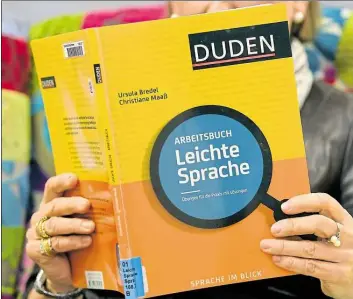  ?? DPA-BILD: JASPERSEN ?? Eine Frau hält in der Stadtbibli­othek ein Arbeitsbuc­h für „Leichte Sprache“in den Händen. Eine Bremer Serviceste­lle überträgt Amtsdeutsc­h in einfache Sprache.