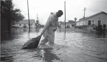  ?? CALLAGHAN O’HARE/THE NEW YORK TIMES ?? A sanitation worker drags a trash bag through water Tuesday in Galveston, Texas, following Tropical Storm Nicholas. The storm, which made landfall as a hurricane, lashed weary residents with wind and heavy rain.