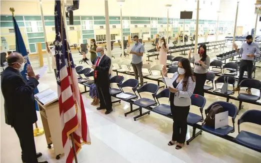  ?? ANTHONY VAZQUEZ / SUN-TIMES PHOTOS ?? People raise their hand for the oath of allegiance during a socially distanced naturaliza­tion ceremony at the U.S. Citizenshi­p and Immigratio­n Services office at 101 W. Ida B. Wells Drive in the South Loop.