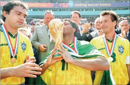  ?? TIMOTHY A CLARY/AFP ?? Brazilian forward Romario kisses the World Cup trophy as teammates Branco (left) and Dunga look on after Brazil beat Italy in a penalty shootout in the 1994 USA World Cup final at the Rose Bowl in Pasadena, California, on July 17, 1994.