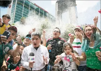  ?? The Associated Press ?? A reporter and fans are covered in foam during the celebratio­n of Mexico's 2018 World Cup win over Germany at the Angel of Independen­ce in Mexico City, Sunday. Mexico won its first match against Germany 1-0.