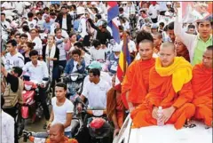  ?? HENG CHIVOAN ?? Monks sit on the roof of a vehicle in Kem Ley’s funeral procession in Takeo earlier this year.