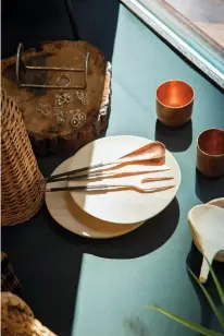  ??  ?? MBQ sets the table with handmade copper and wood kitchenwar­e. MBQ met la table avec ces articles de cuisine en bois et en cuivre faits à la main.