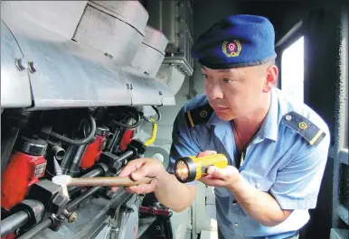  ?? PROVIDED TO CHINA DAILY ?? Zhang Xiaojun inspects his freight train’s engine before starting a round trip between China and Russia on a 9.8-kilometer railway line that connects the two countries’ rail networks.