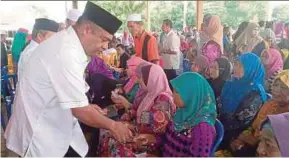  ?? PIC BY SHARIFAH MAHSINAH ABDULLAH ?? Datuk Seri Abdul Azeez Abdul Rahim distributi­ng aid in Kota Baru yesterday.