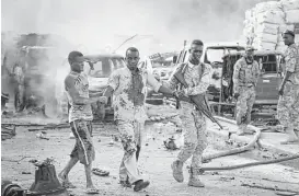  ?? Farah Abdi Warsameh / Associated Press ?? A Somali soldier helps a civilian who was wounded in a blast that killed 20 and wounded 15 Saturday in Mogadishu, Somalia. Shaken residents called it the most powerful blast they’d heard in years. No group has claimed responsibi­lity.