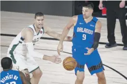  ??  ?? Magic center Nikola Vucevic, passing the ball to forward Gary Clark in front of Bucks center Brook Lopez, scored a playoff career-high 35 points Tuesday. AP